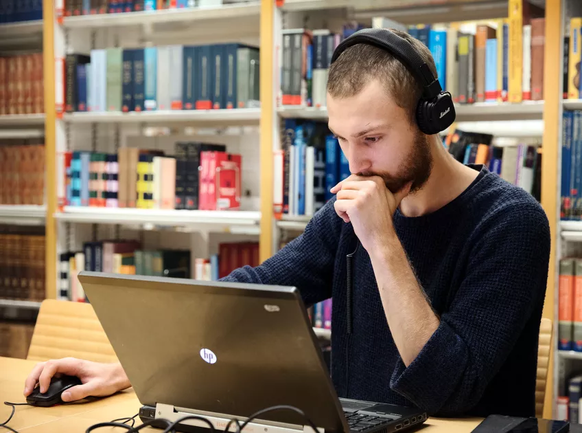 A student with headphones is working on his laptop. Photo: Johan Bävman.