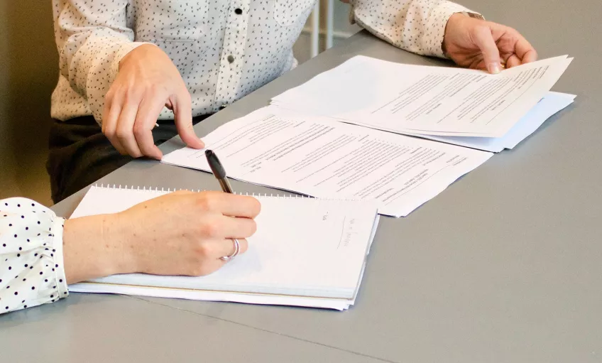 Two people going through a document and taking notes. Photo.